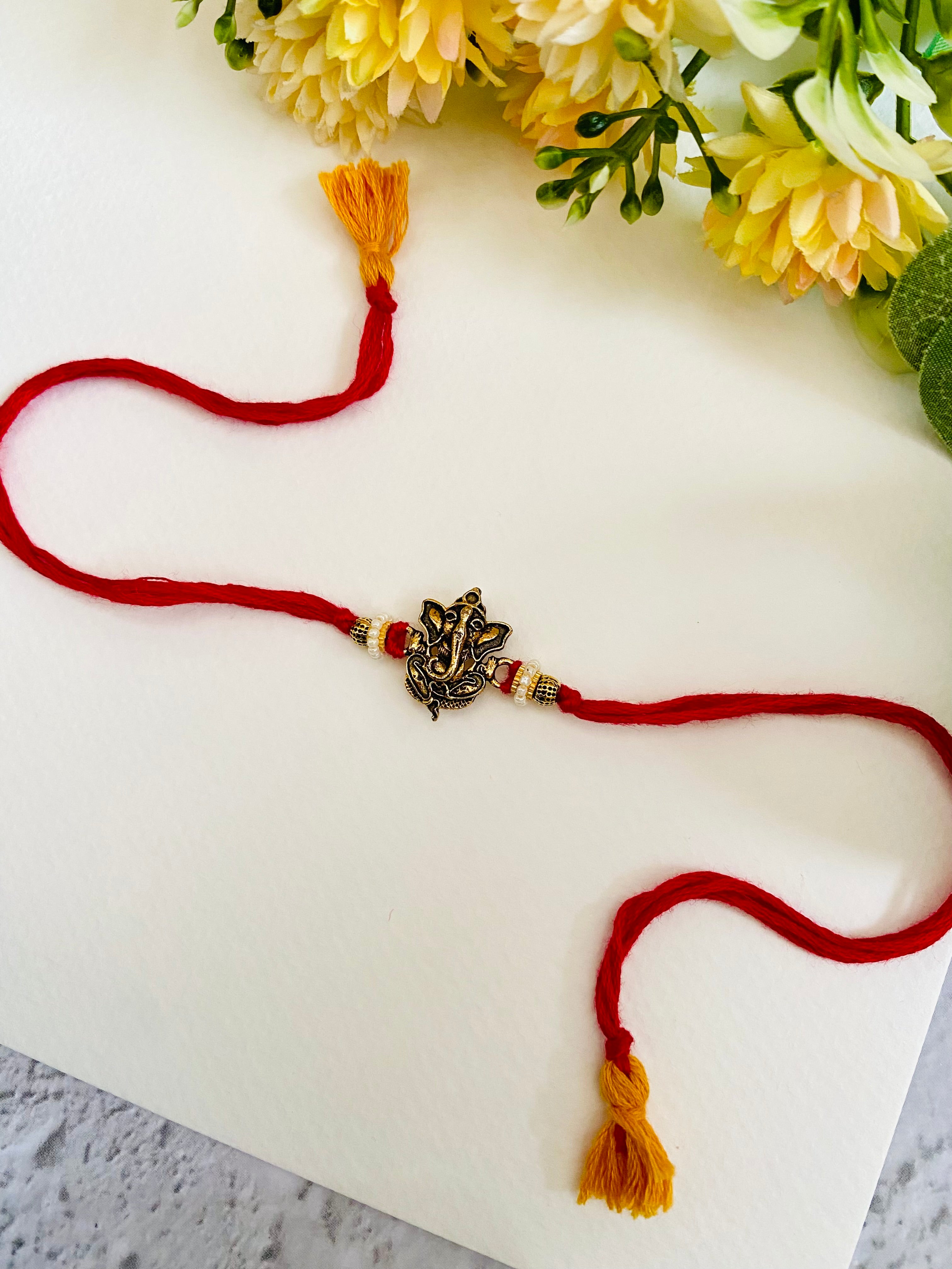 Purpledip Rakhi – Cesto Regalo Per Fratello: Ganesha In Marmo Chopra, 2 Rakhi, Roli Chawal Tika – Confezione Rossa Festiva